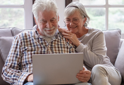 senior couple of couch with laptop