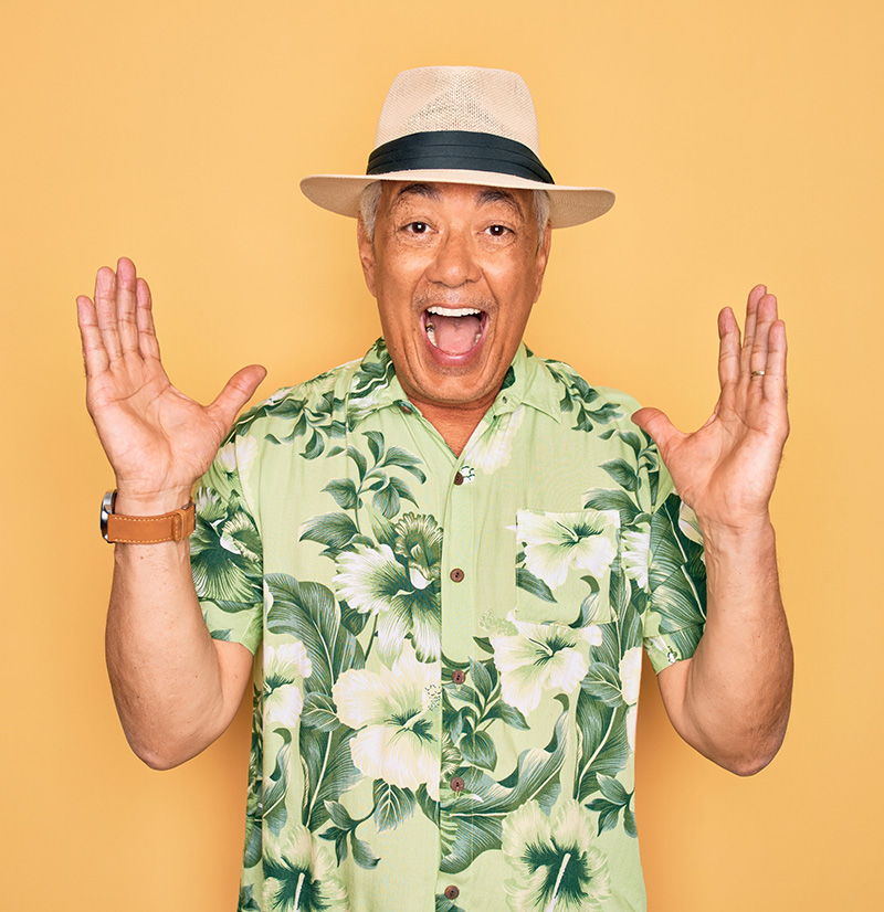 Middle age senior grey-haired man wearing summer hat and floral shirt celebrating and amazed with arms raised and open eyes screaming excited.