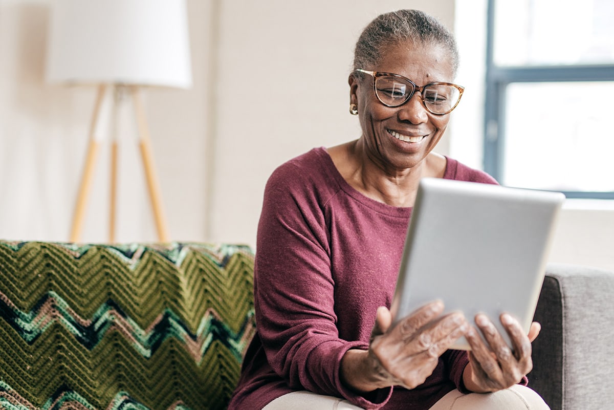 A senior looking at a tablet on her couch